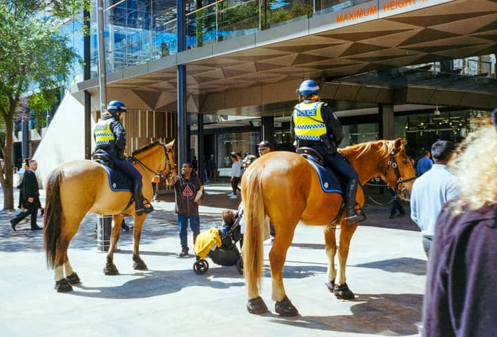 Two mounted police officers on patrol in a bustling urban street area.