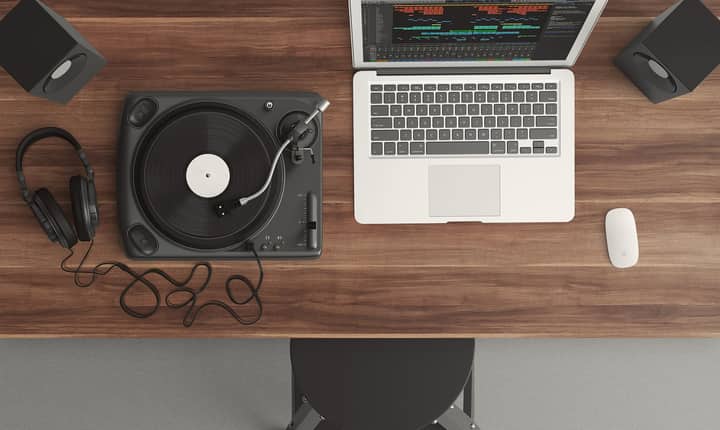 Top view of a music production desk with a laptop and turntable setup for modern audio production.