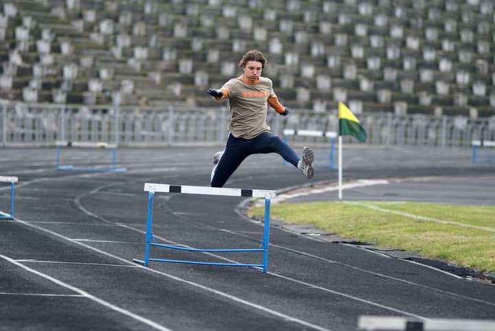 Athlete demonstrating speed and agility while jumping hurdles during track event.