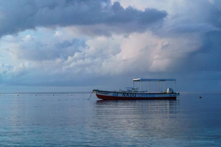Tranquil seascape featuring a lone boat, ideal for diving enthusiasts, under an overcast sky.