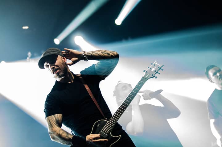 Energetic guitarist rocking out on stage during a live music performance under bright lights.