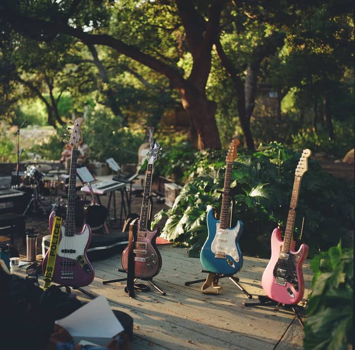An array of colorful electric guitars set on an outdoor stage ready for a summer music festival performance.