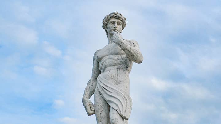 Low angle view of Michelangelo's David sculpture under a blue sky, showcasing its classical art beauty.