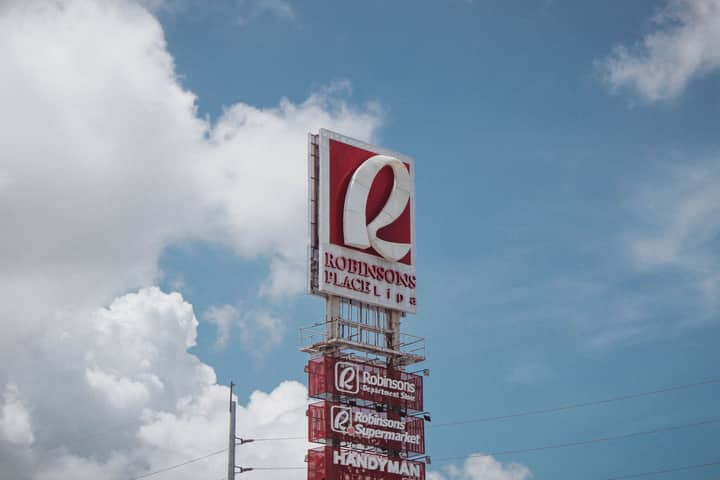 Iconic Robinsons Place Lipa sign with a vibrant blue sky and fluffy clouds.