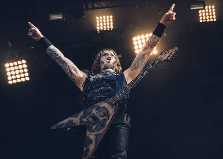 Energetic rock musician with tattoos playing electric guitar during live performance.