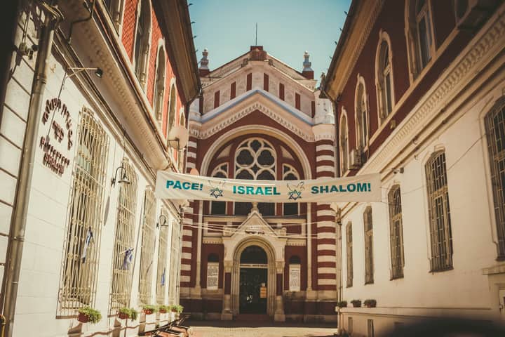Gothic Revival architecture of Brașov Synagogue with a peace message banner under daylight.