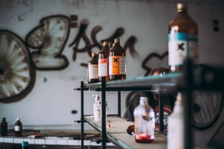 Discover an abandoned industrial room featuring shelves of toxic chemical bottles and graffiti walls.