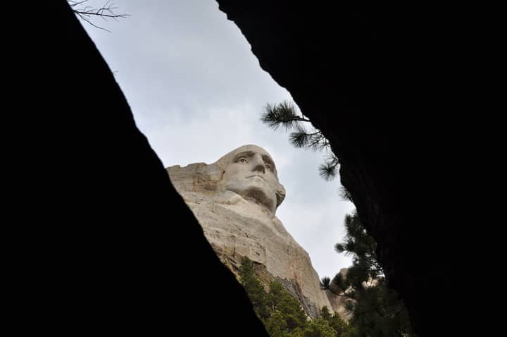 Explore a unique perspective of Mount Rushmore, capturing its grandeur through natural framing.