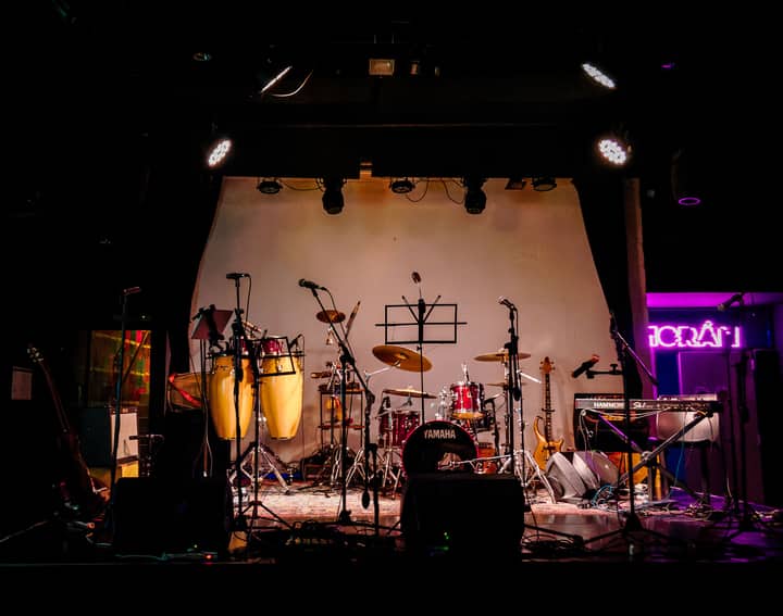 An empty stage set with musical instruments ready for a live performance in a dimly lit venue.