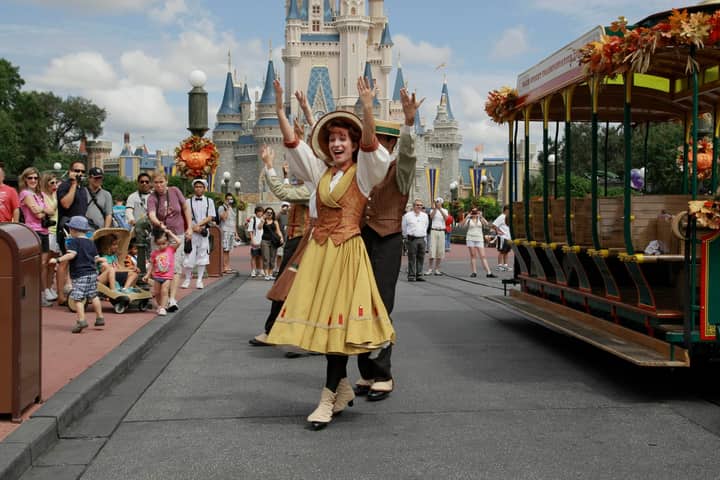 Colorful parade with performers in front of iconic castle, capturing festive atmosphere and joyous crowd.