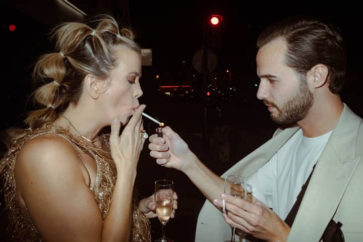Elegant nightlife scene with friends enjoying champagne and a cigarette under city lights.
