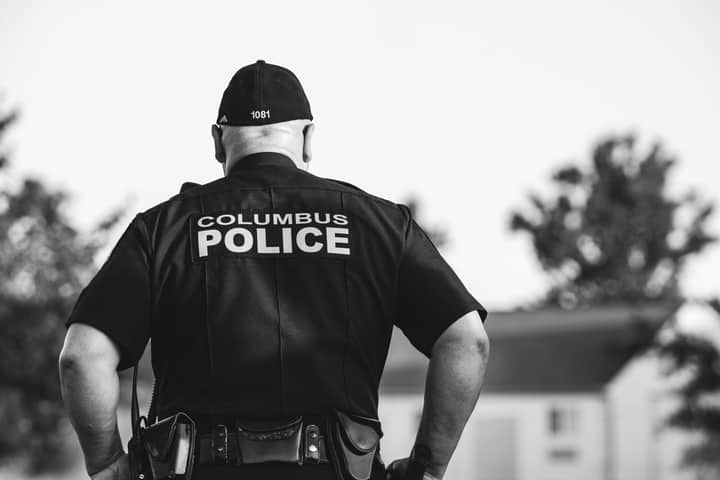 Black and white photo of a police officer in uniform from Columbus, outdoors, in focus.