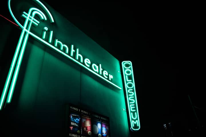 Vibrant neon film theater sign glowing at nighttime.