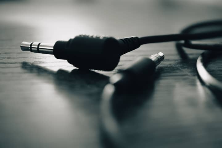 Black and white close-up of an audio jack on a wooden table.