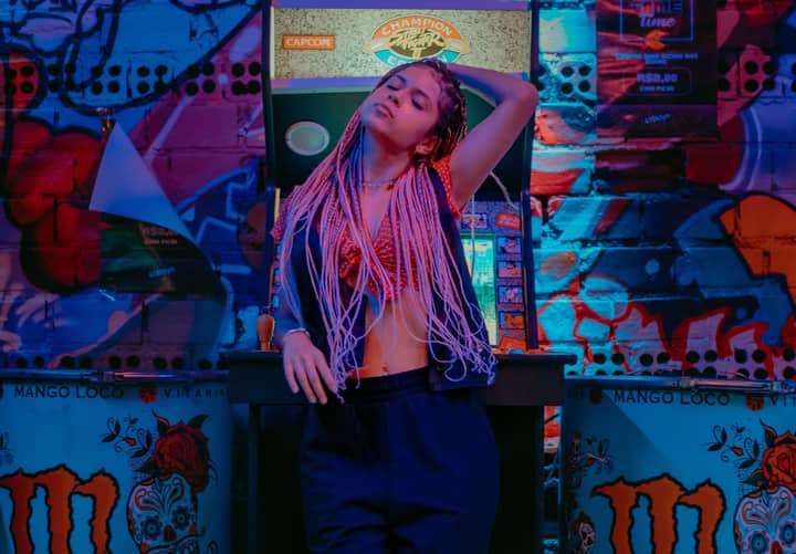 Stylish woman in a nightclub setting with vibrant graffiti and arcade machine background.
