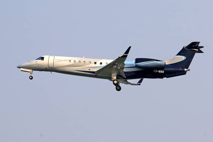 Embraer Legacy 600 private jet flying in clear blue sky, showcasing sleek design and elegance.