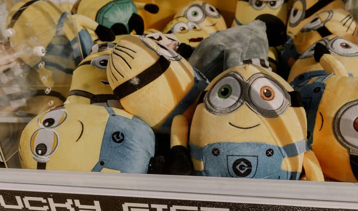 A collection of vibrant minion plush toys inside an arcade claw machine, perfect for entertainment.