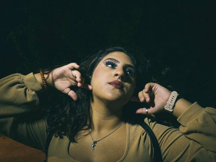 A striking portrait of a woman gazing up with dramatic lighting and raised hands.
