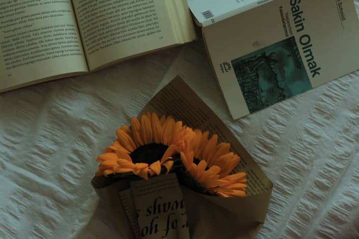 A serene still life of sunflowers and books on a soft fabric surface.