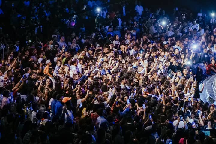 A vibrant crowd enjoying a live concert with phones raised to capture the performance.
