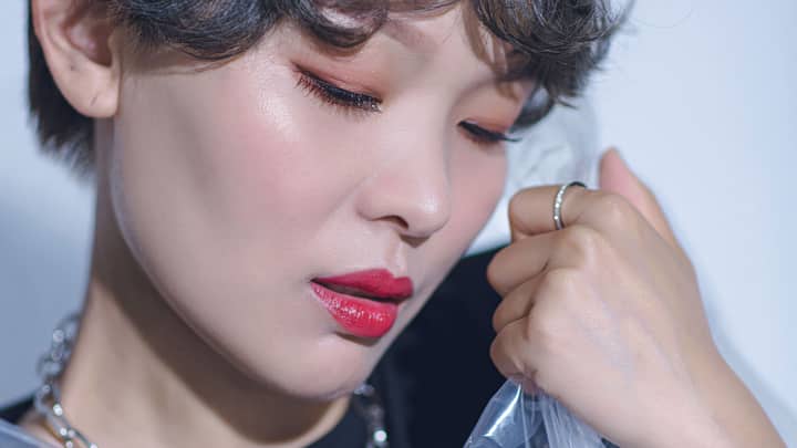 A close-up portrait of a woman with bold makeup and short hair, showcasing beauty and elegance.
