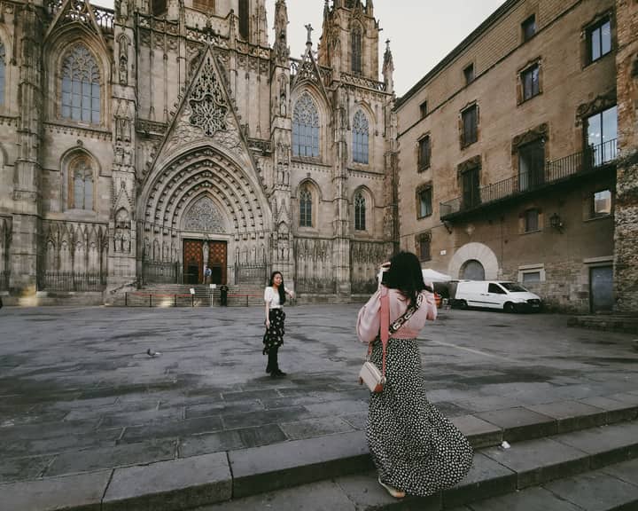 Two women capture the Gothic facade of Barcelona Cathedral, a landmark of Christian heritage in Spain.