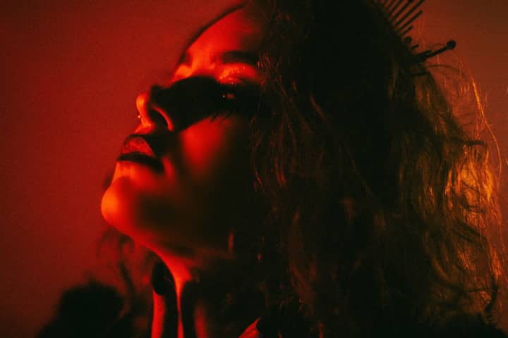 Atmospheric portrait of a woman with edgy makeup and moody red lighting.