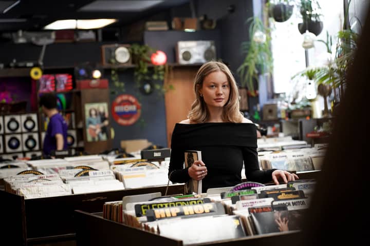 A woman looking through vinyl records in a vintage record store filled with eclectic decor.