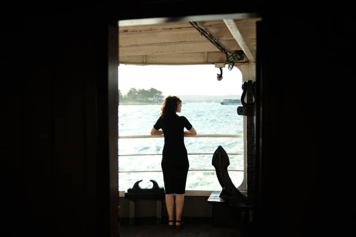 A woman standing on a cruise ship deck, gazing at the ocean, symbolizing relaxation and travel.