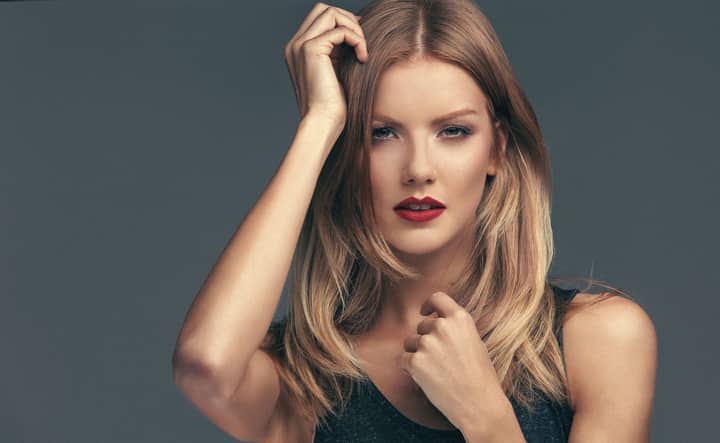 Close-up portrait of a blonde woman with red lipstick posing in a studio setting.
