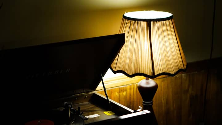 A dimly lit vintage setup featuring a gramophone and a warm glowing table lamp.