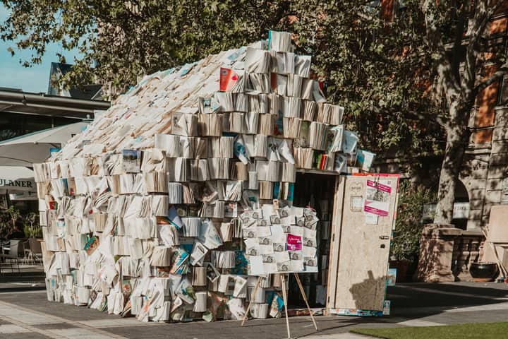 Unique architectural structure made entirely of books, showcasing creativity and literature in an urban outdoor location.
