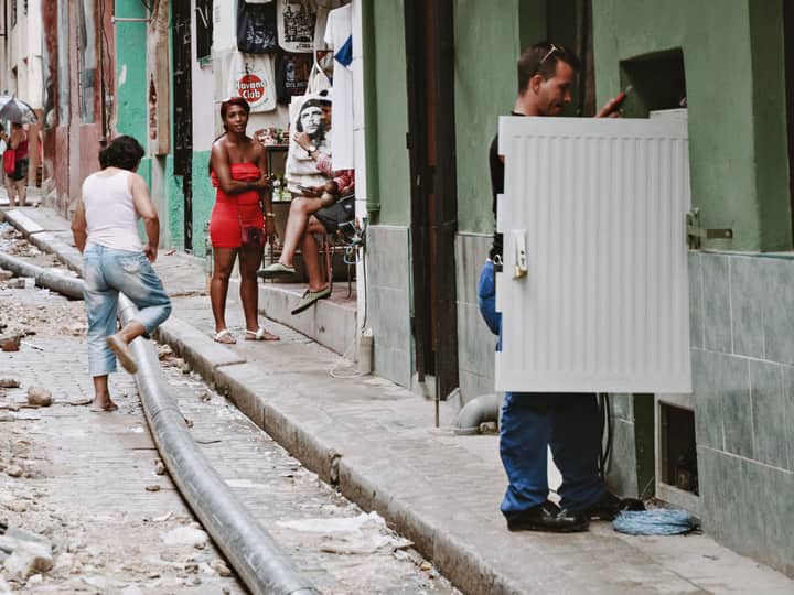 A lively street scene in Havana showcasing diverse people and ongoing street repairs.