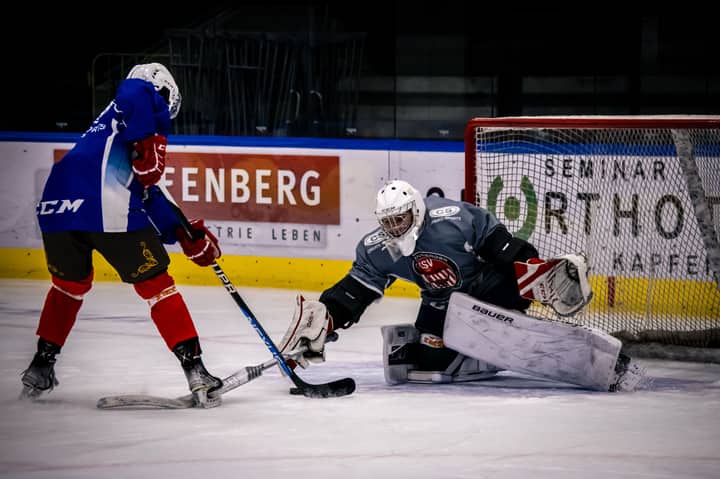 Exciting ice hockey match with players in action on the rink, featuring a dynamic goalkeeper save.