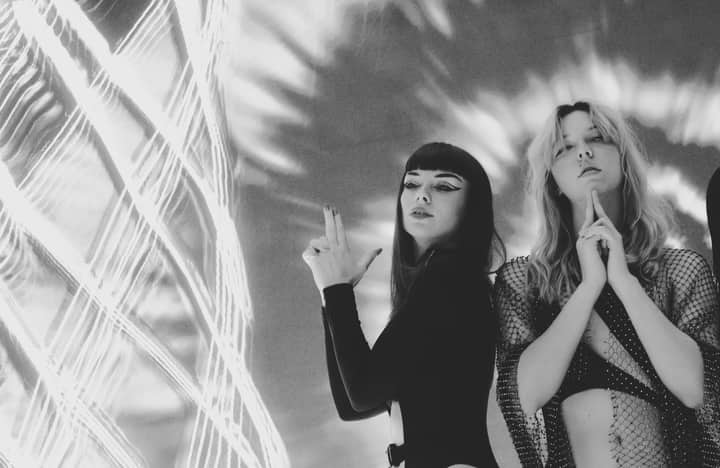 Two women posing creatively in black and white with artistic lighting patterns.