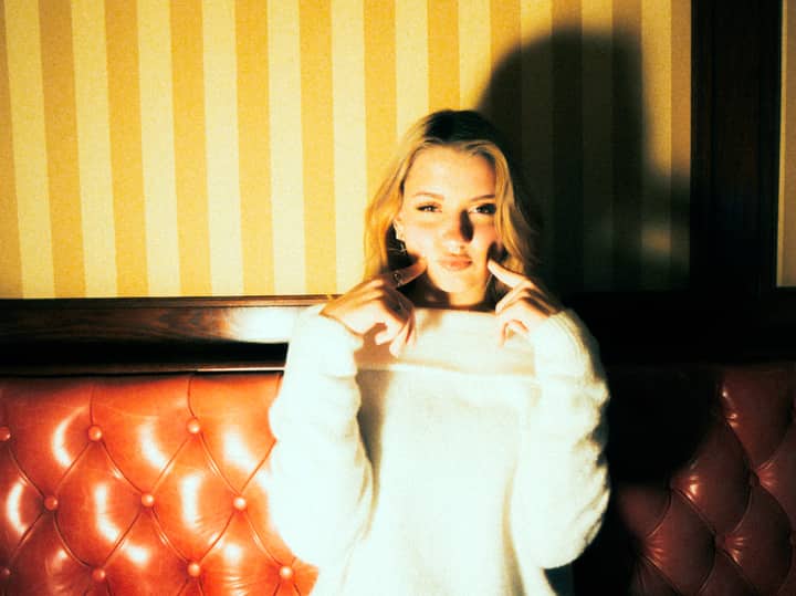 Elegant woman with blonde hair posing indoors with dramatic lighting.