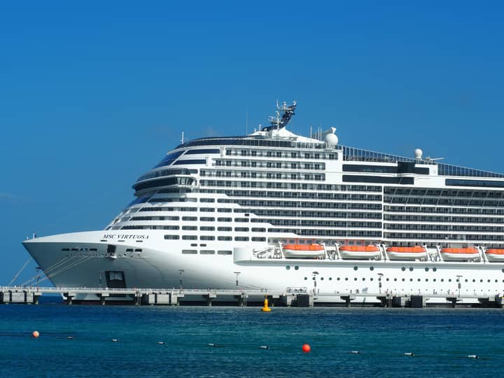 A breathtaking view of the MSC Virtuosa cruise ship docked in a sunny harbor.