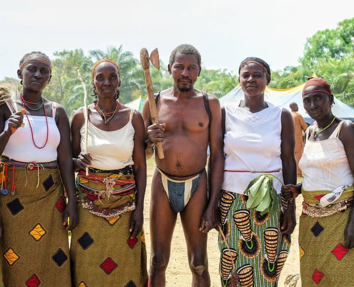 A group of African adults in traditional tribal clothing posing outdoors, showcasing cultural heritage.