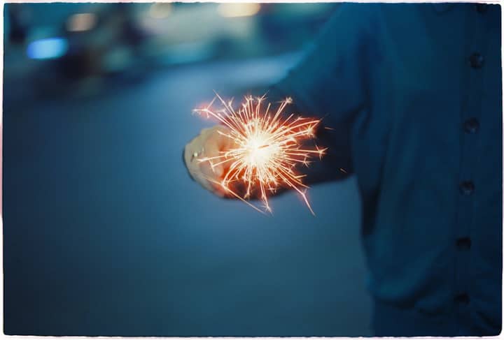 A person holds a sparkling firework, illuminating the night with joy and celebration.
