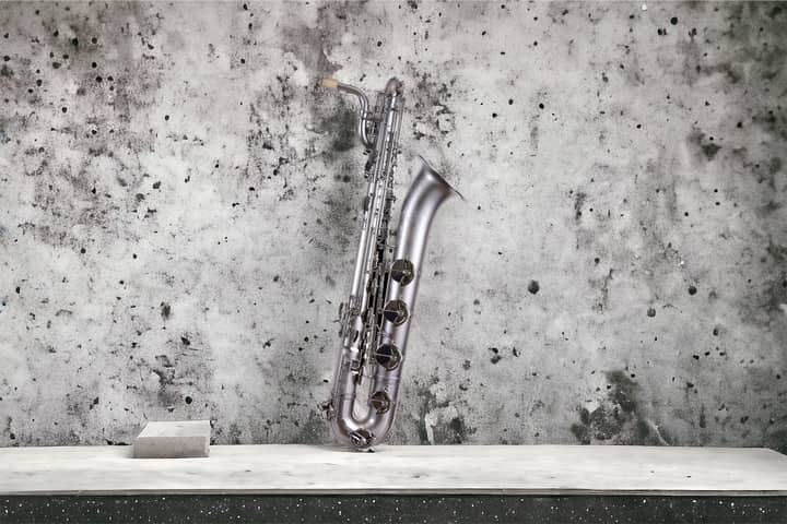 A silver saxophone elegantly leaning against a textured concrete wall, highlighting its classic design.