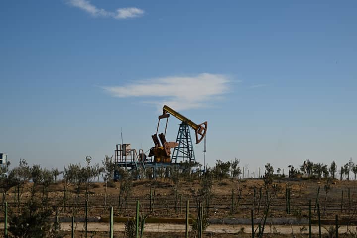 Oil pump jack in a dry landscape with shrubs and clear sky in Bakú, Azerbaijan.