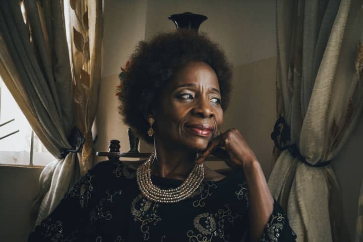 Portrait of an older woman with curly hair and jewelry, reflecting elegance and wisdom.