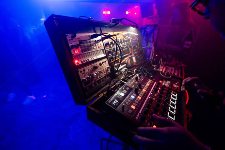 Captivating club scene with a DJ using an electronic mixing console in vibrant lighting.