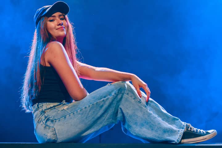 Contemporary portrait of a young woman in casual fashion, sitting and smiling in a vibrant setting.