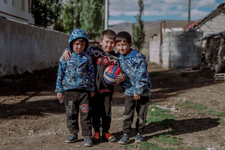 Three children enjoy outdoor play with a colorful ball in Van, Türkiye.