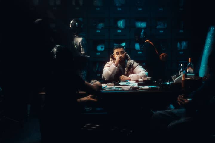 A group gathered around a table with bottles and papers, set in a dimly lit room.