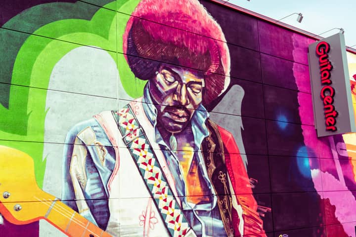 Colorful street art mural of a music legend painted on Guitar Center wall.