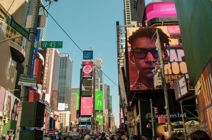 Lively daytime scene in Times Square, New York, showing towering skyscrapers and vibrant billboards.