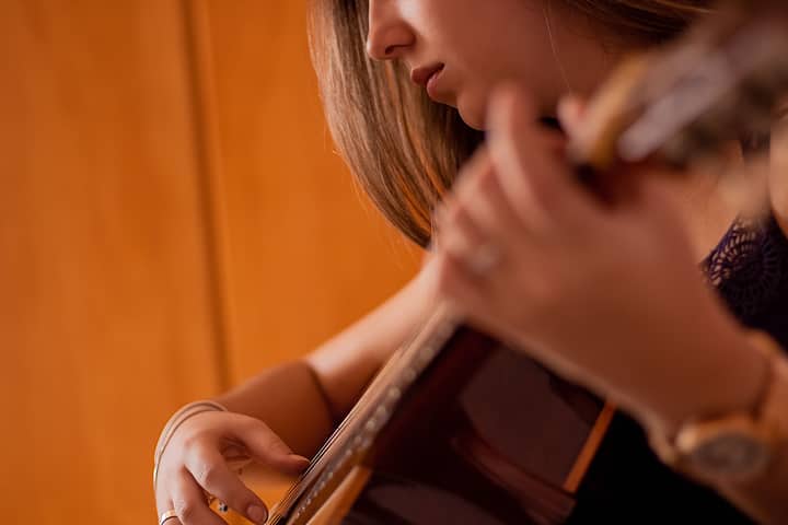 Focused shot of a woman skillfully playing an acoustic guitar indoors.