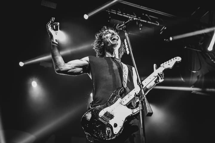 Black and white photo capturing an energetic guitarist performing live on stage.